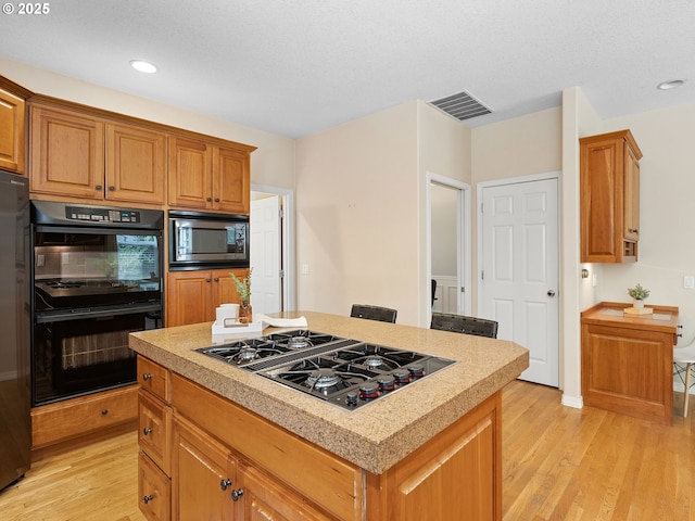 17712 SW 81st Pl, Durham, OR 97224 - kitchen featuring black appliances, light wood-type flooring, light countertops, a center island, and recessed lighting