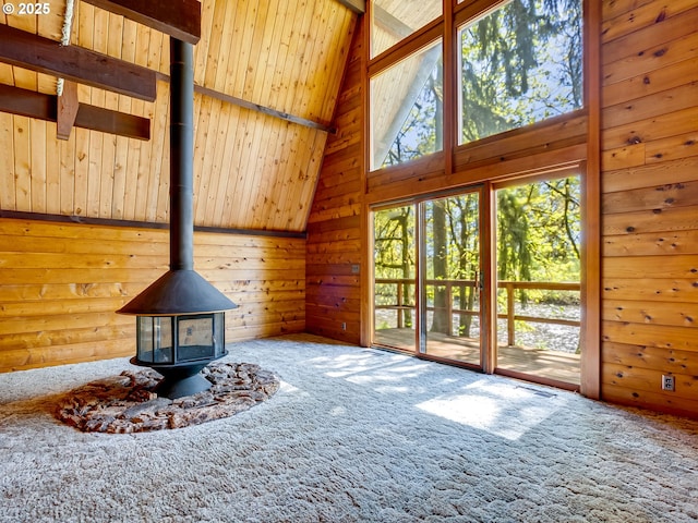 26619 NE 77th Ave, Battle Ground, WA 98604 - unfurnished living room with carpet floors, a wood stove, lofted ceiling with beams, and wood walls