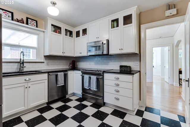 1556 Washington St, Eugene, OR 97401 - kitchen with appliances with stainless steel finishes, a sink, light floors, dark countertops, and backsplash