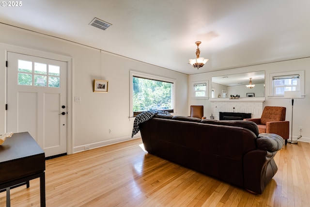 1556 Washington St, Eugene, OR 97401 - living room featuring a fireplace, light wood-type flooring, a chandelier, and baseboards