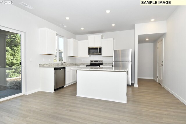 5329 NE 68th St, Vancouver, WA 98661 - kitchen with light wood-type flooring, white cabinetry, a kitchen island, visible vents, and appliances with stainless steel finishes
