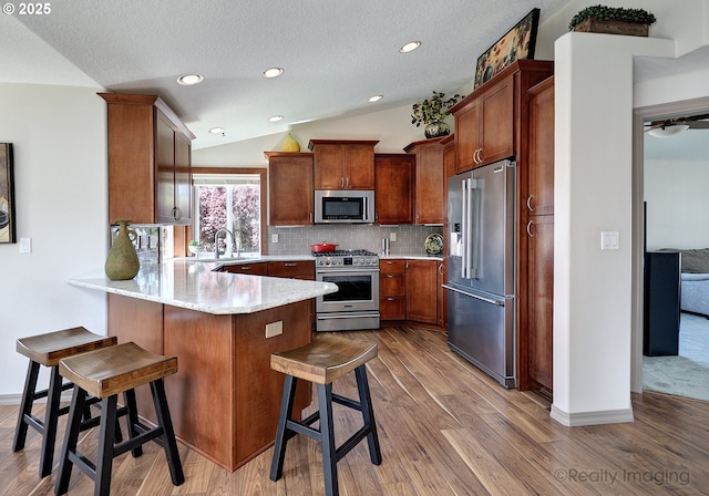 9312 NE 30th Ave, Vancouver, WA 98665 - kitchen featuring high end appliances, a peninsula, light wood-style flooring, lofted ceiling, and a textured ceiling