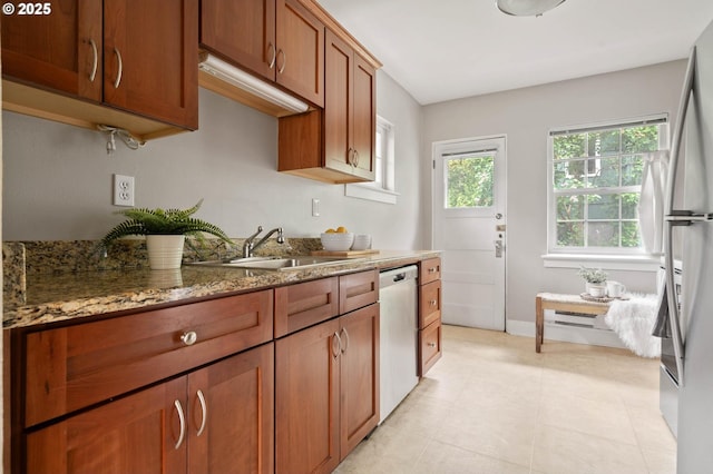 2643 NW Raleigh St Unit 30, Portland, OR 97210 - kitchen featuring appliances with stainless steel finishes, a sink, light stone counters, brown cabinetry, and baseboards