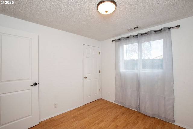 unfurnished bedroom featuring visible vents, light wood-style flooring, and a textured ceiling