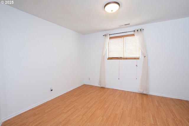 unfurnished room with visible vents, light wood-style flooring, and baseboards