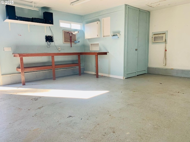 garage featuring an AC wall unit and baseboards