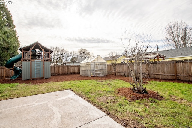 view of yard featuring an outbuilding, an exterior structure, a playground, and a fenced backyard