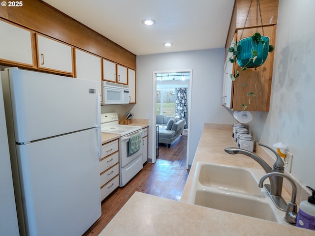 kitchen with a sink, wood finished floors, white cabinetry, white appliances, and light countertops