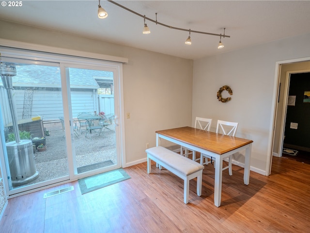 dining room featuring track lighting, visible vents, light wood-type flooring, and baseboards