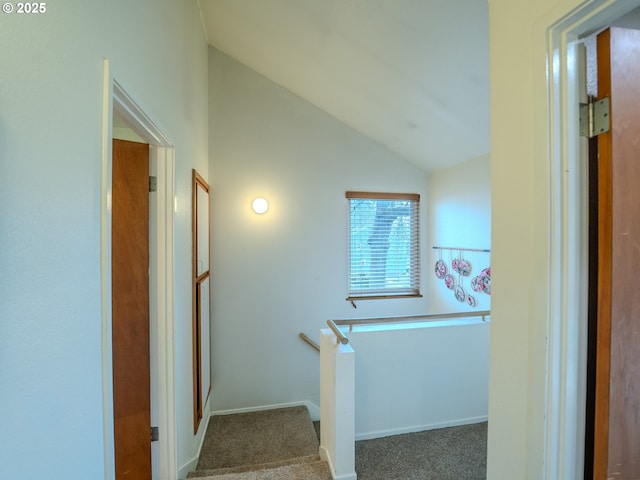 corridor with baseboards, carpet, and vaulted ceiling