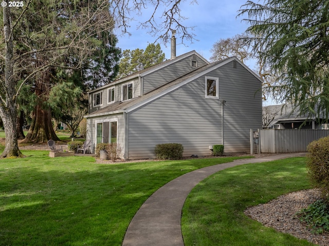 view of side of home featuring a lawn and fence