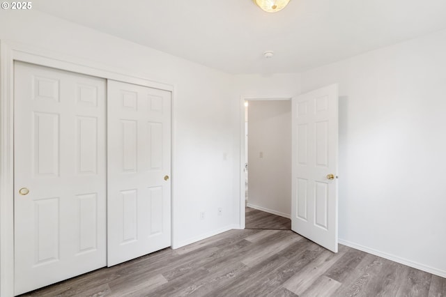 unfurnished bedroom with wood finished floors, a closet, and baseboards