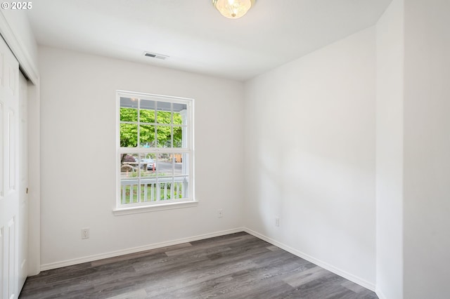 unfurnished bedroom with dark wood finished floors, a closet, and baseboards