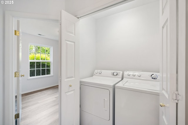 clothes washing area featuring washing machine and clothes dryer and light wood-style flooring