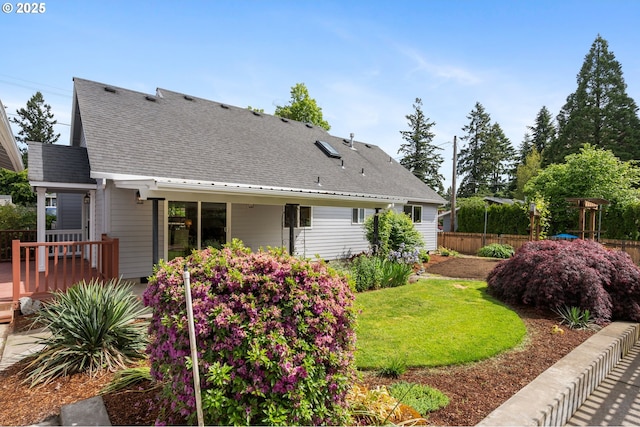 rear view of property featuring roof with shingles and a deck