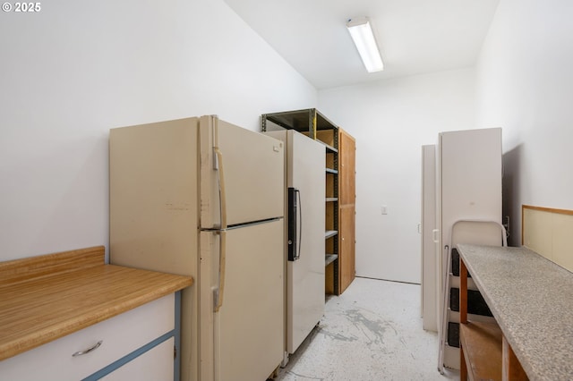 kitchen featuring freestanding refrigerator, light countertops, and open shelves