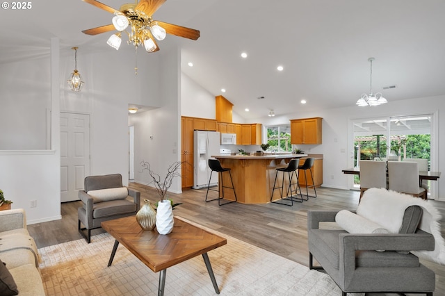living room with a chandelier, high vaulted ceiling, ceiling fan, recessed lighting, and light wood finished floors