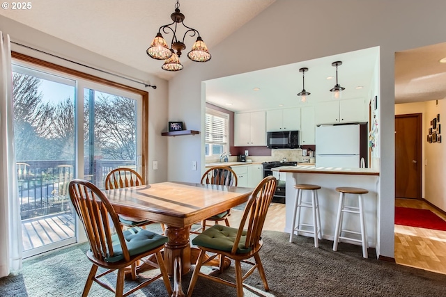 dining room featuring carpet flooring, lofted ceiling, sink, and a chandelier