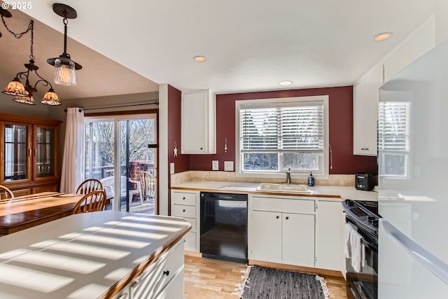 kitchen with pendant lighting, black appliances, white cabinets, sink, and plenty of natural light