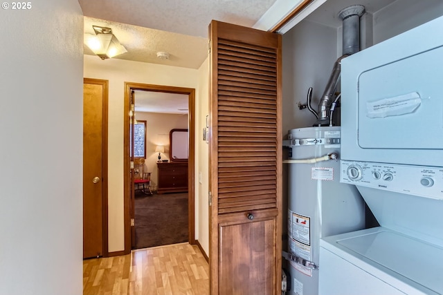 laundry area with secured water heater, a textured ceiling, light hardwood / wood-style flooring, and stacked washer / dryer