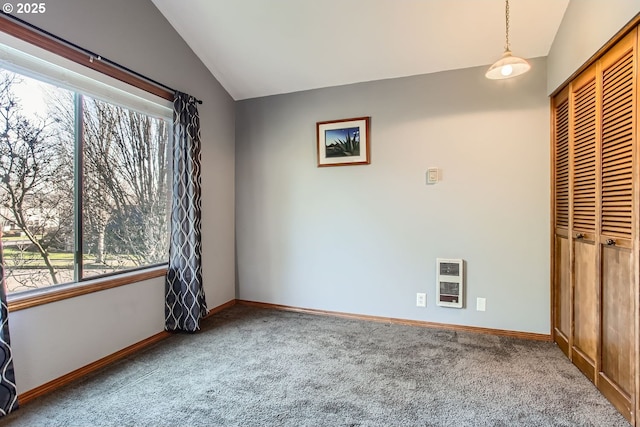 unfurnished bedroom featuring heating unit, a closet, carpet floors, and lofted ceiling