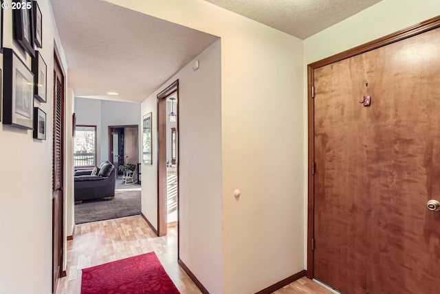 hall with light hardwood / wood-style flooring and a textured ceiling