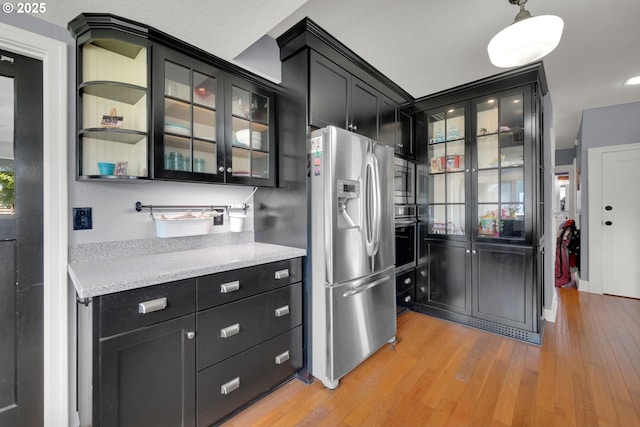 683 Laurel, Junction City, OR 97448 - kitchen featuring stainless steel appliances, dark cabinets, light countertops, light wood finished floors, and glass insert cabinets