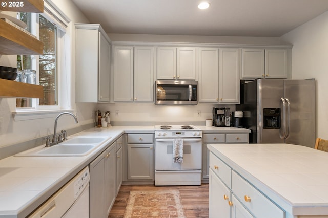 5862 SE Woodland Dr, Gresham, OR 97080 - kitchen featuring tile counters, light wood-type flooring, a sink, and appliances with stainless steel finishes