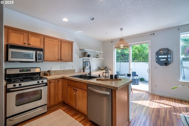 12115 NE 40th Cir, Vancouver, WA 98682 - kitchen featuring a peninsula, a sink, a textured ceiling, light wood-type flooring, and appliances with stainless steel finishes