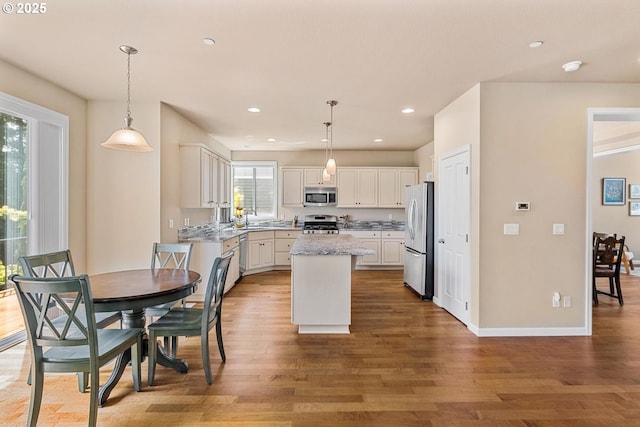 2814 NW Hill St, Camas, WA 98607 - kitchen with appliances with stainless steel finishes, a center island, light wood-style flooring, white cabinets, and hanging light fixtures
