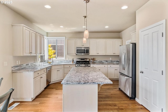 2814 NW Hill St, Camas, WA 98607 - kitchen with stainless steel appliances, a center island, light wood finished floors, light stone counters, and recessed lighting
