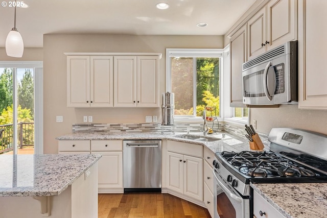 2814 NW Hill St, Camas, WA 98607 - kitchen with stainless steel appliances, decorative light fixtures, light stone counters, light wood-style floors, and recessed lighting