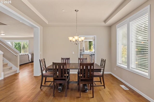 2814 NW Hill St, Camas, WA 98607 - dining room featuring a tray ceiling, light wood-style floors, a chandelier, and stairway