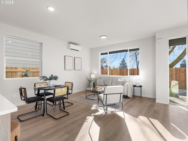 living room with a wall mounted AC and light wood-type flooring