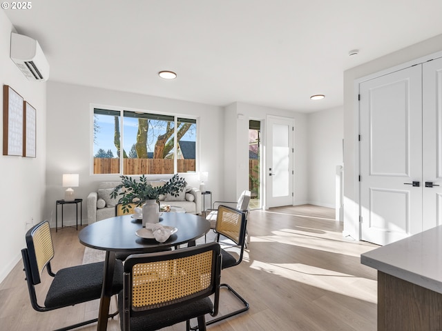 dining room with light hardwood / wood-style flooring and a wall unit AC