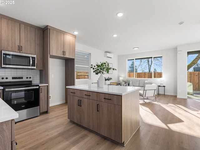 kitchen featuring a kitchen island, backsplash, light hardwood / wood-style flooring, and appliances with stainless steel finishes