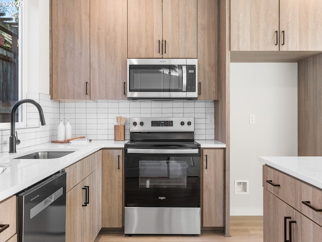 kitchen with stainless steel appliances, tasteful backsplash, sink, and light hardwood / wood-style floors