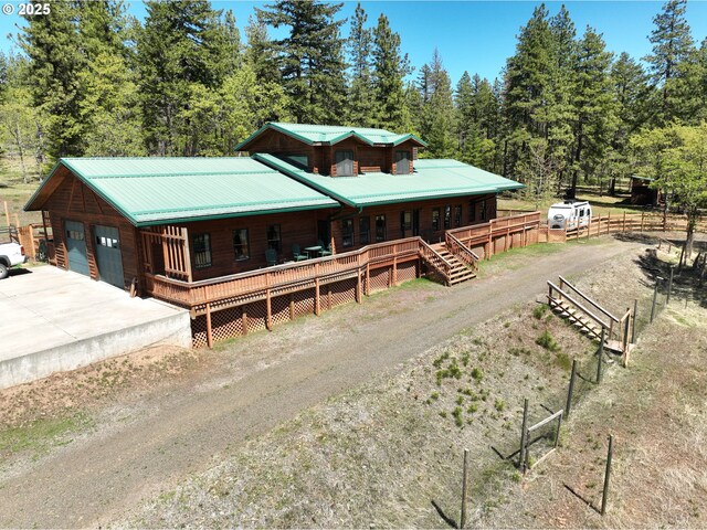 view of front of property with a porch, dirt driveway, metal roof, and fence