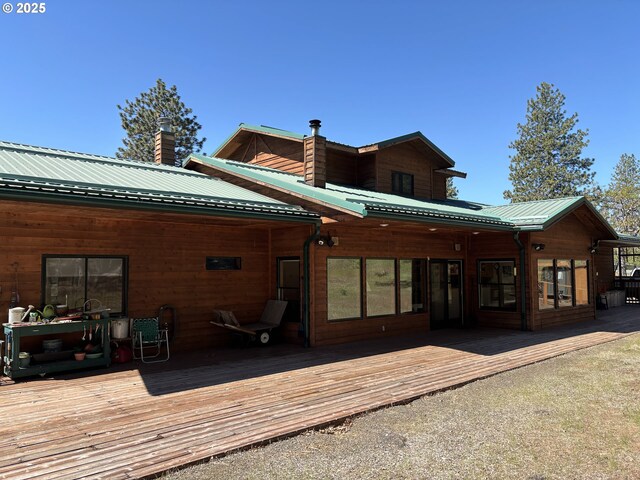 rear view of property featuring metal roof, a deck, and a chimney