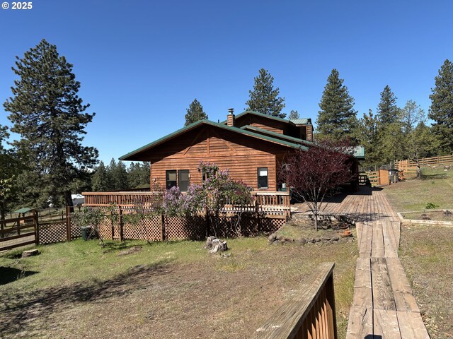 view of property exterior featuring a chimney, a wooden deck, and fence