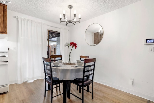 9259 SE Clay St, Portland, OR 97216 - dining space featuring a chandelier, light wood-style floors, a textured ceiling, and baseboards
