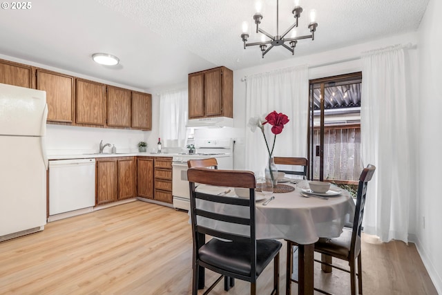 9259 SE Clay St, Portland, OR 97216 - kitchen featuring white appliances, brown cabinetry, light wood-style floors, a chandelier, and a textured ceiling