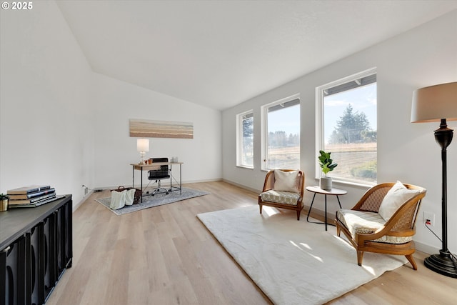 living area with plenty of natural light, light hardwood / wood-style floors, and vaulted ceiling