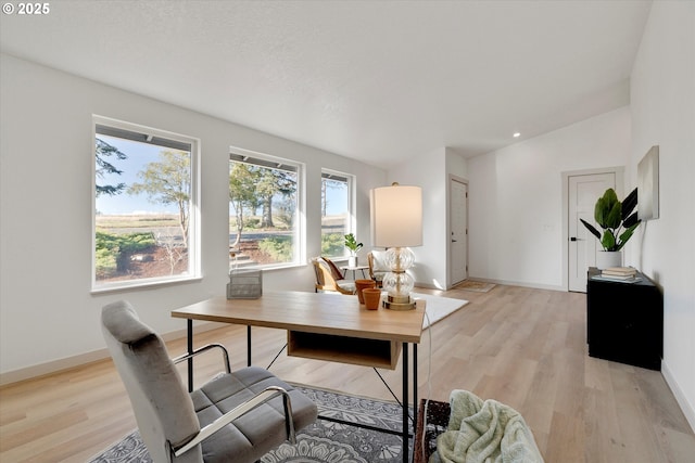 office space with vaulted ceiling and light hardwood / wood-style floors