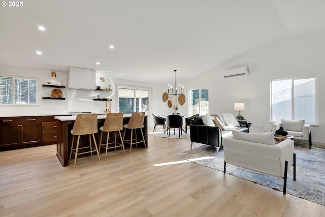 interior space featuring a kitchen breakfast bar, lofted ceiling, a wall mounted air conditioner, and light wood-type flooring