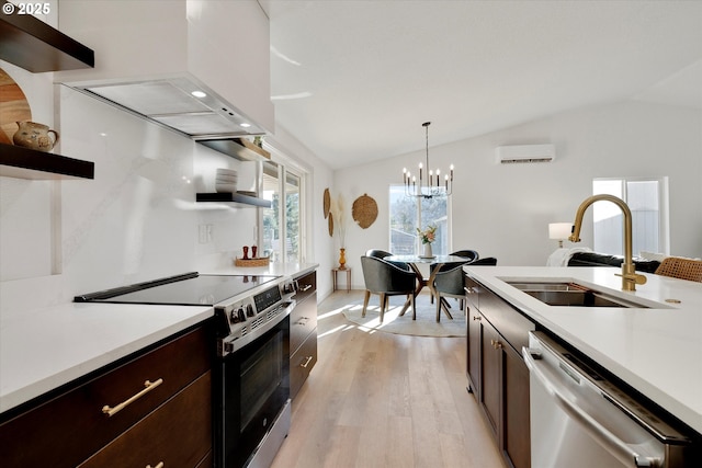 kitchen featuring lofted ceiling, sink, appliances with stainless steel finishes, a wall unit AC, and pendant lighting