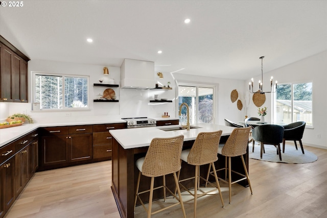 kitchen featuring sink, stainless steel electric range, light hardwood / wood-style flooring, a center island with sink, and custom exhaust hood