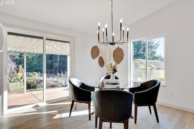 dining room with lofted ceiling, an inviting chandelier, and light hardwood / wood-style floors