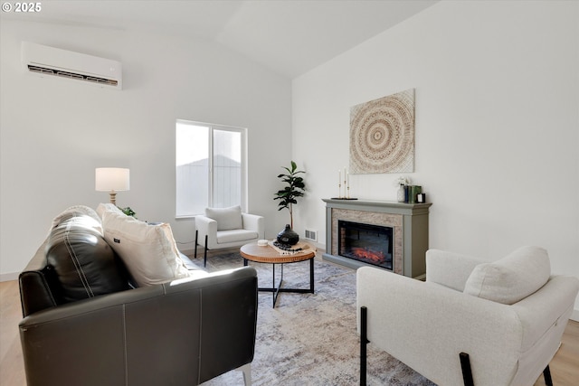 living room featuring light hardwood / wood-style flooring, a wall mounted air conditioner, and vaulted ceiling