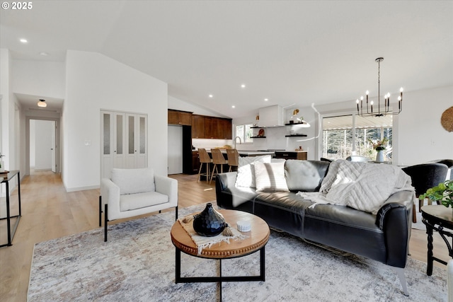 living room featuring an inviting chandelier, lofted ceiling, and light hardwood / wood-style flooring